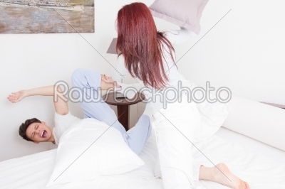 girl in pajamas hitting boy with pillow