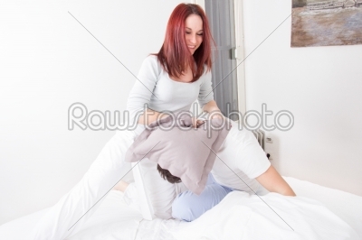 girl in pajamas hitting boyfriend with pillow