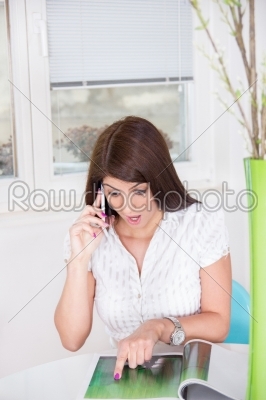 girl on the phone at home while reading the magazine