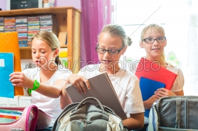 Girls prepare bags for school with books 