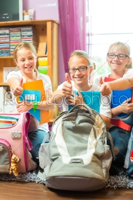 Girls prepare bags for school with books 