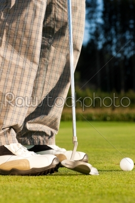 Golf player putting ball into hole