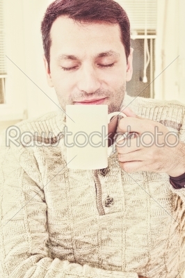 Good looking adult man savouring the aroma of a cup of fresh hot