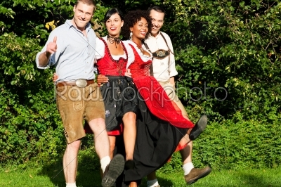 Group of four friends in Bavarian Tracht dancing