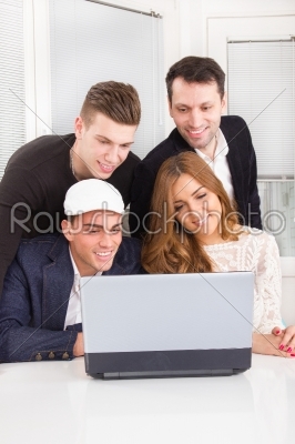 group of friends and colleagues looking at laptop together