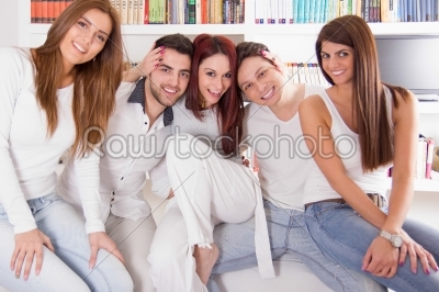 group of friends smiling and sitting together on sofa at home