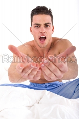half naked handsome man in bed with hands out towards camera
