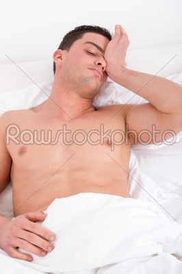 half naked man waking up in the bedroom and stretches in bed