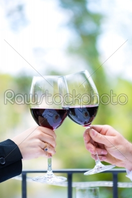 Hands holding red wine glasses to clink