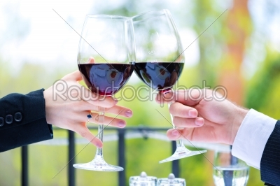 Hands holding red wine glasses to clink