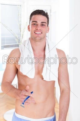 handsome guy with razor in hand after shaving smiling