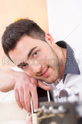 handsome man  leaning on his guitar and smiling