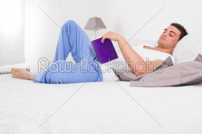 handsome man reading book in his bed