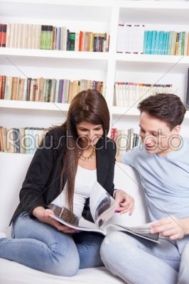 happy couple at home reading newspapers in front of library