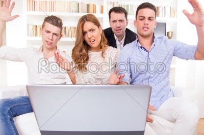 hocked casual group of friends sitting on couch looking at lapto