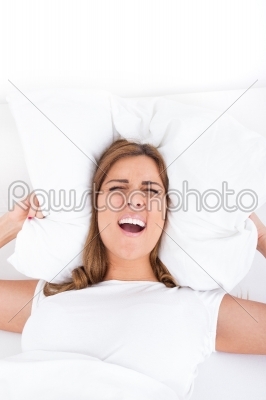 Image of irritated female lying on bed and closing her ears with