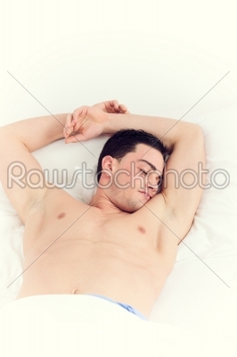 Image of man with both hands up on pillow sleeping in bed