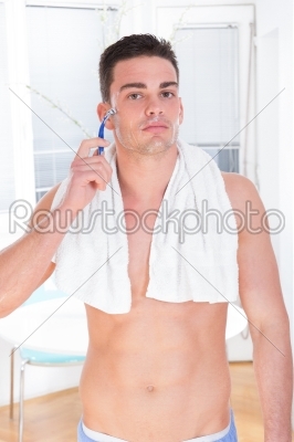 male model shaving wearing towel around neck and pajamas