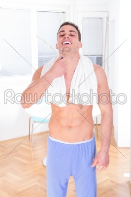 man in pajamas shaving beard with razor in the morning