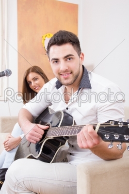 man in white shirt playing guitar and singing