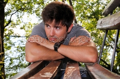 man leaning on a bench in the park