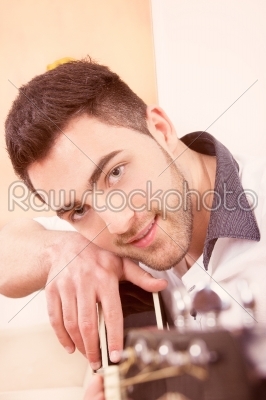 Man leaning on his guitar smiling