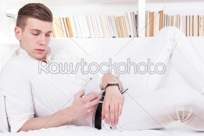man lying on the couch texting message on cellphone