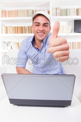 man relaxing at home with laptop computer showing thumbs up