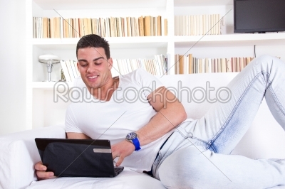 man relaxing on sofa with laptop computer