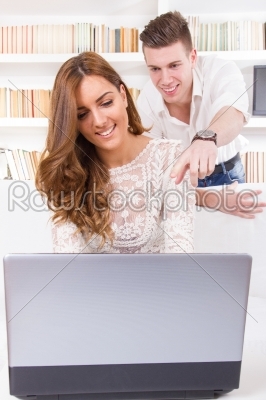 man showing something on the laptop screen to his girlfriend