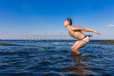Naked young man coming out from the water