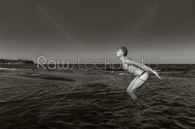 Naked young man coming out from the water in black and white