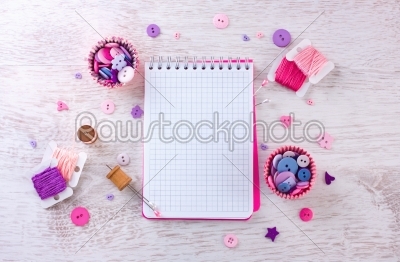 notebook with sewing items.  a check fabrics, buttons, thread and pins