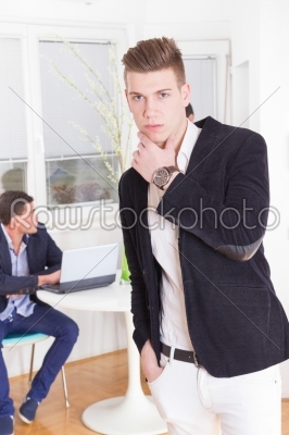 pensive handsome business man with colleague in background using