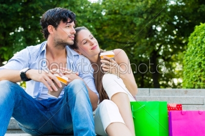 people or couple in city park with shopping bags