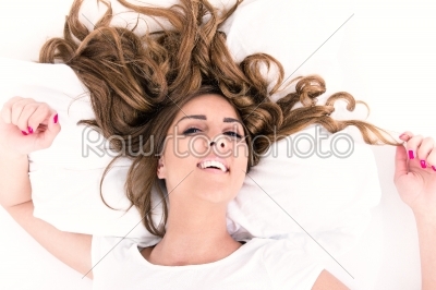 portrait of young woman lying in bed with hair spread around