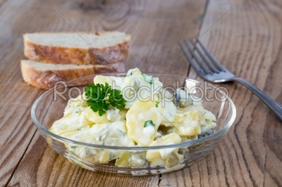 Potato salad in a glass bowl on wooden board