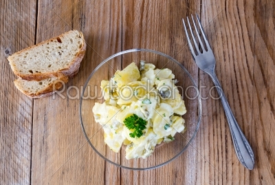 Potato salad in a glass bowl on wooden board