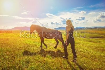pretty girl leading a horse across the meadow