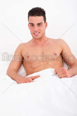 proud attractive man lying in bed with naked torso smiling