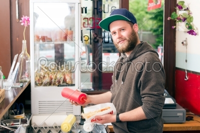 salesman making hotdog in fast food snack bar