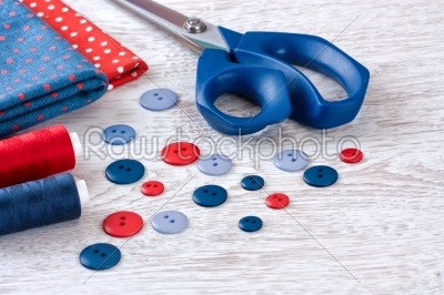 scissors, threads, fabric  and  buttons on wooden table