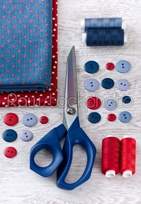 scissors, threads, fabric and buttons on wooden table