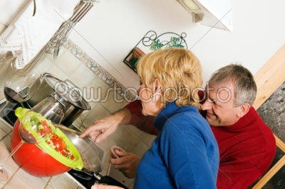 Senior couple cooking dishes in kitchen