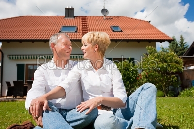 Senior couple sitting in front of their home