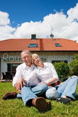 Senior couple sitting in front of their home