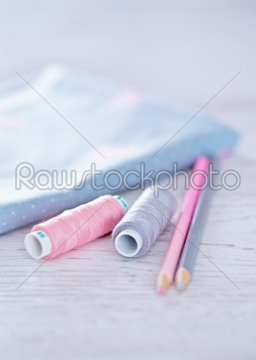 sewing materials, pencils, fabric on a blue and pink color