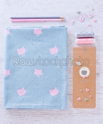 sewing materials, pencils, note, fabric on blue and pink color