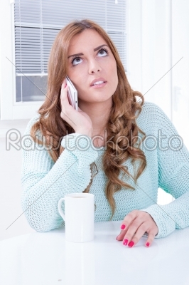 thoughtful girl talking on the phone with cup of coffee