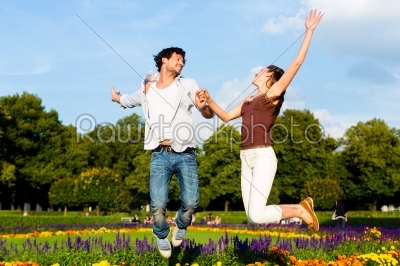 Tourist couple in city park jumping in sun